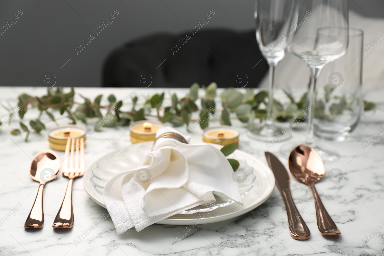 Photo of Beautiful place setting with candles and eucalyptus on white marble table