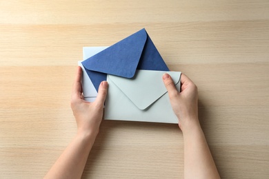 Photo of Woman with paper envelopes at wooden table, top view