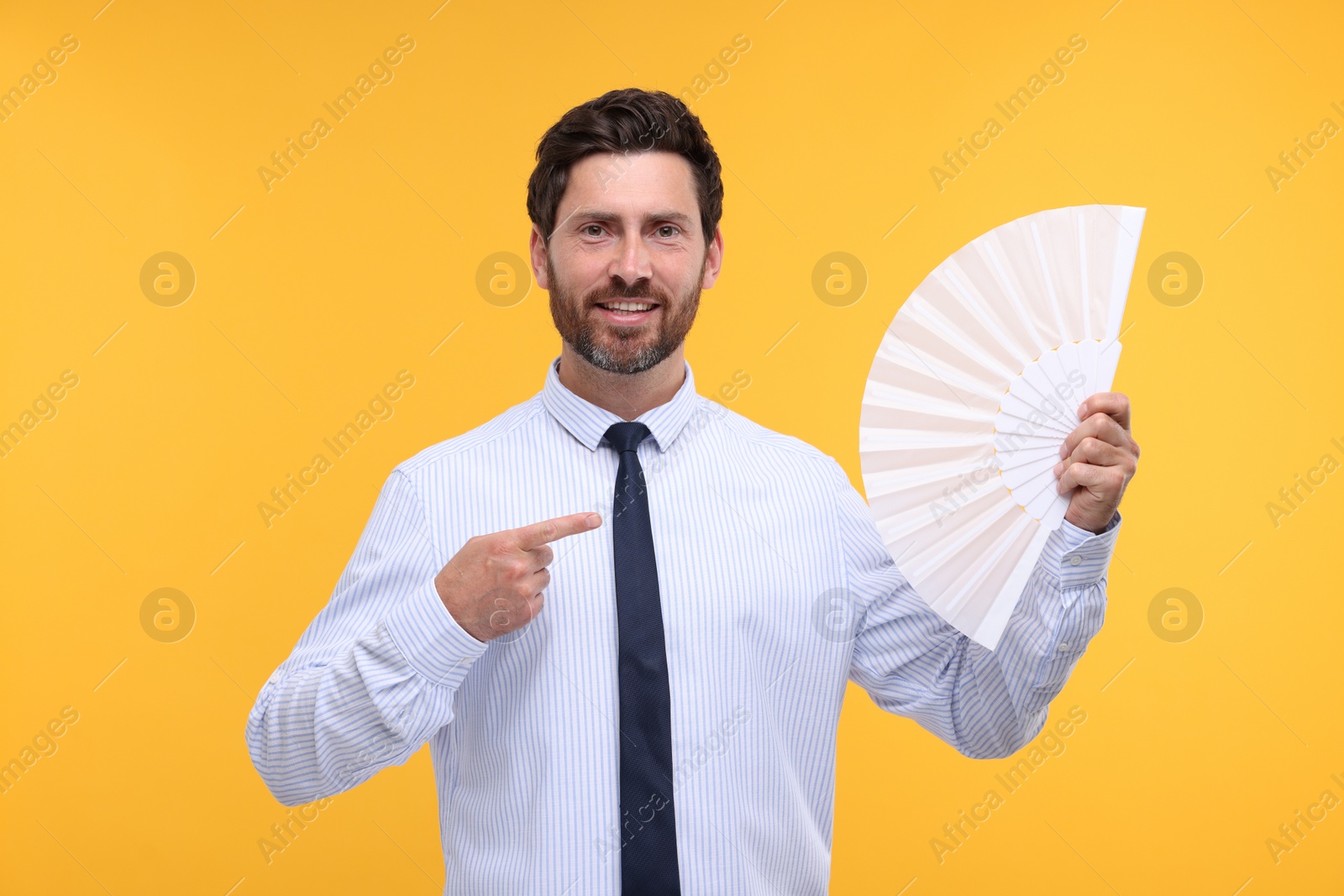 Photo of Happy man holding hand fan on orange background