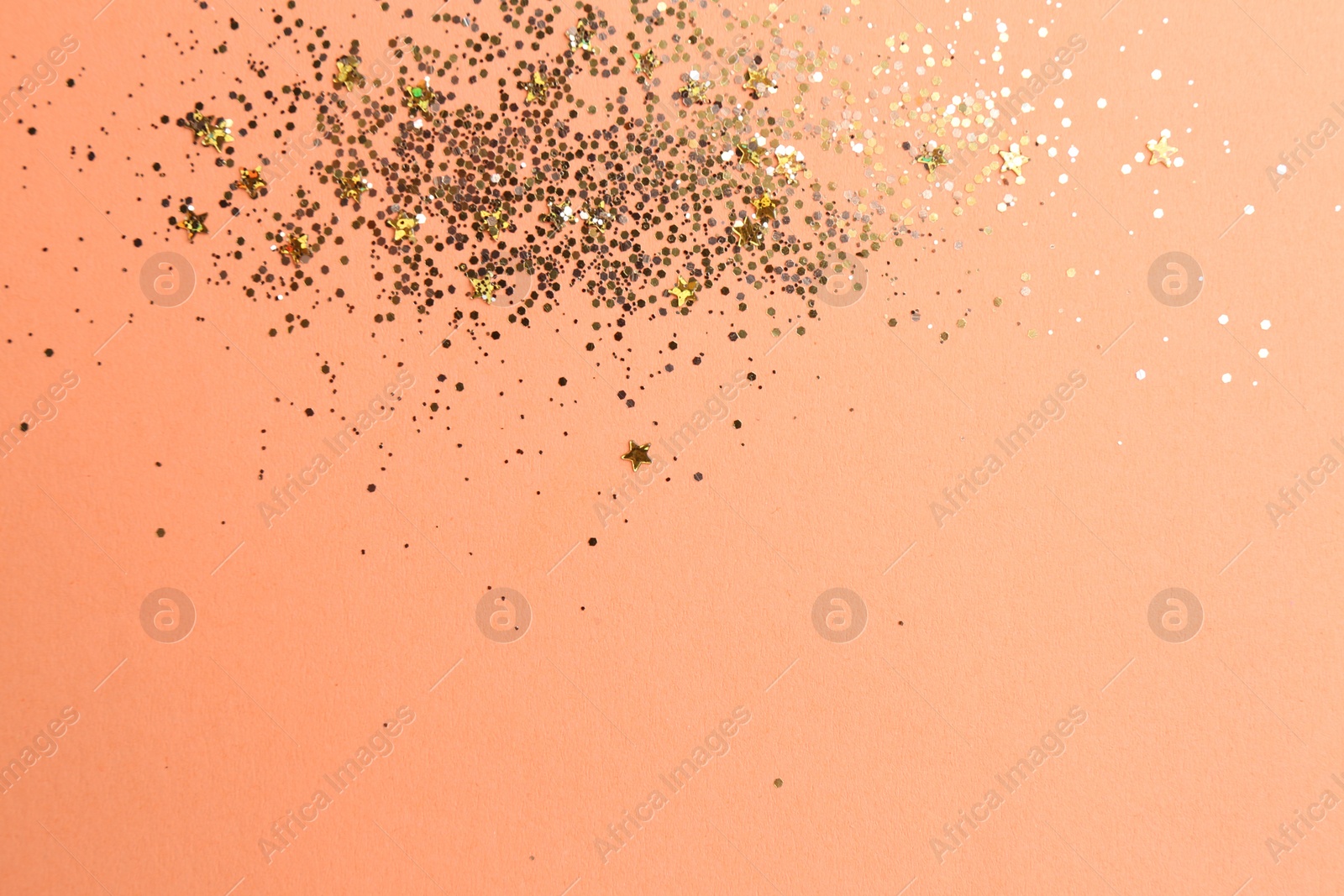 Photo of Shiny bright golden glitter on pale coral background, flat lay. Space for text