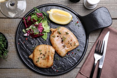 Grilled squid tubes served on wooden table, flat lay