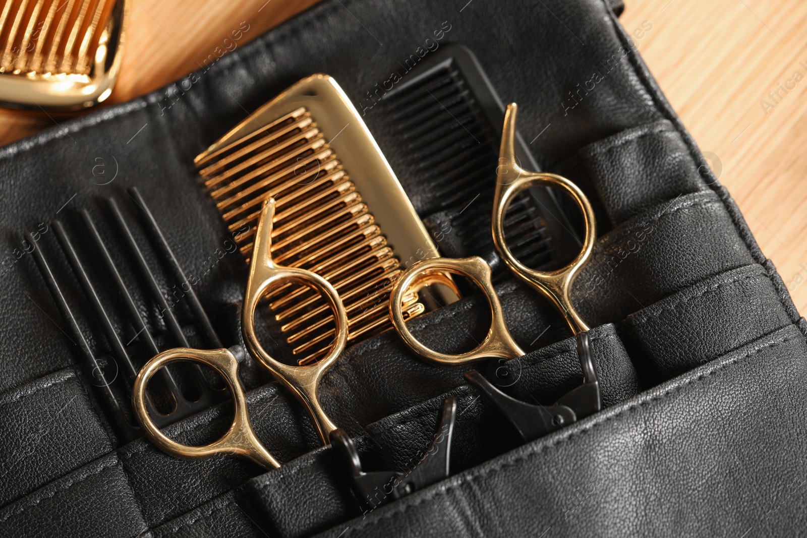 Photo of Hairdresser tools. Professional scissors and combs in leather organizer on wooden table, top view