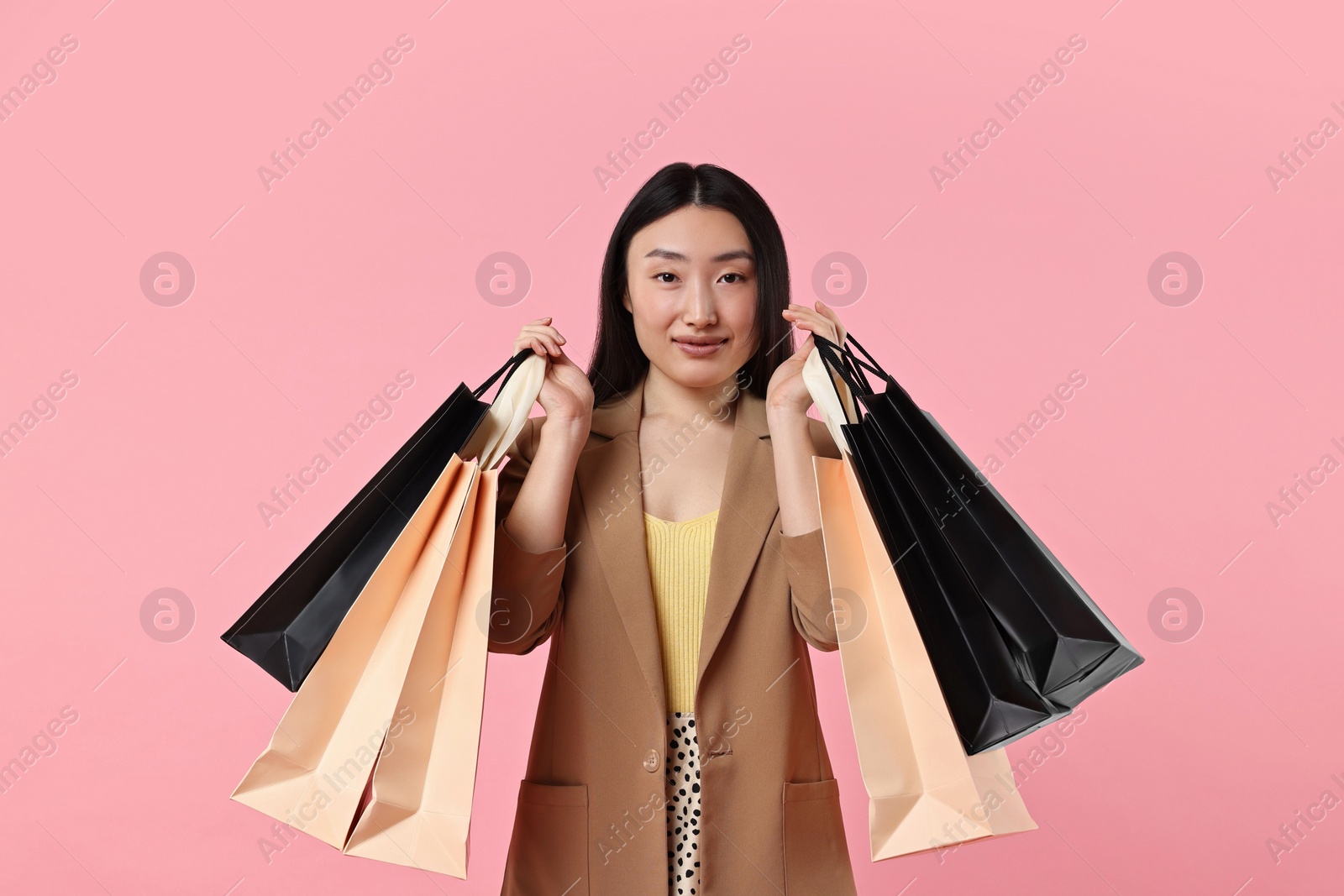 Photo of Beautiful woman with shopping bags on pink background
