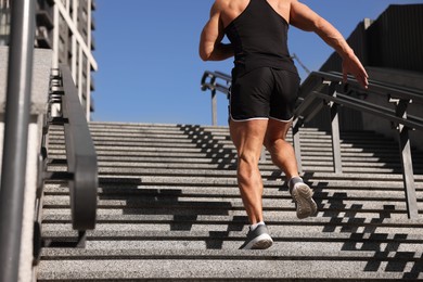 Man running up stairs outdoors on sunny day, closeup