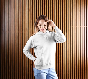 Portrait of woman in hoodie sweater on wooden background. Space for design