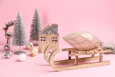Photo of Beautiful Christmas composition with miniature sleigh on pink background