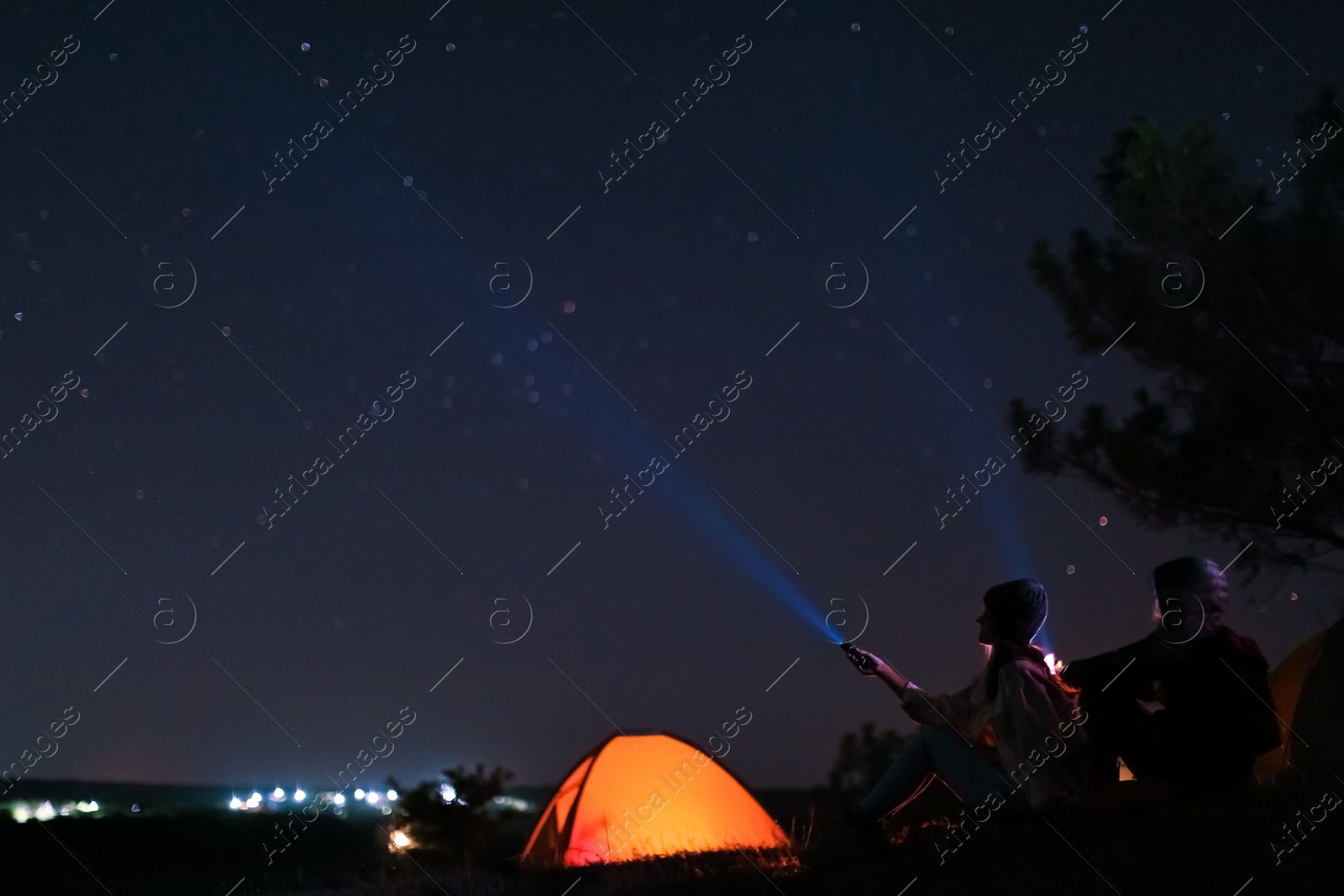 Photo of Couple with flashlights near camping tent outdoors at night