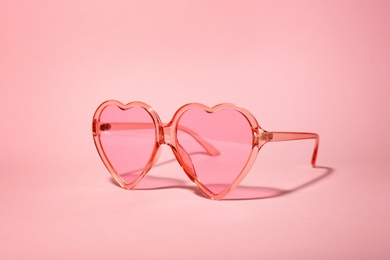 Photo of Stylish heart shaped glasses on color background