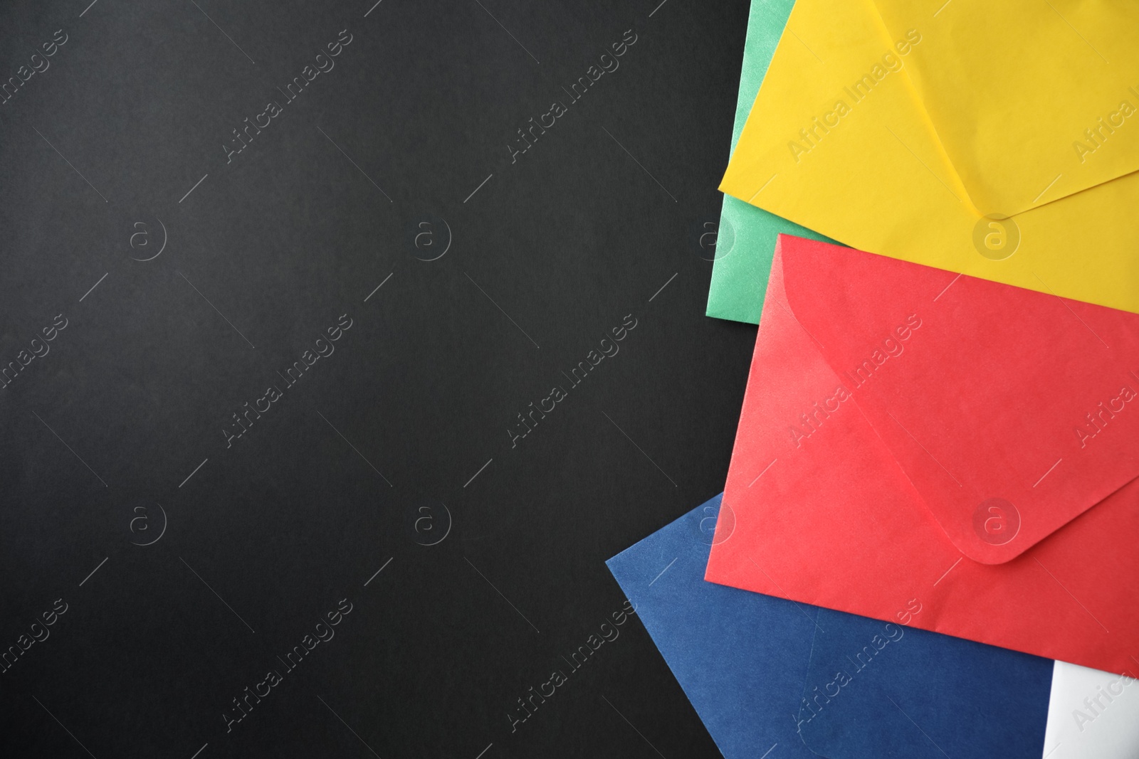 Photo of Colorful paper envelopes on black background, flat lay. Space for text