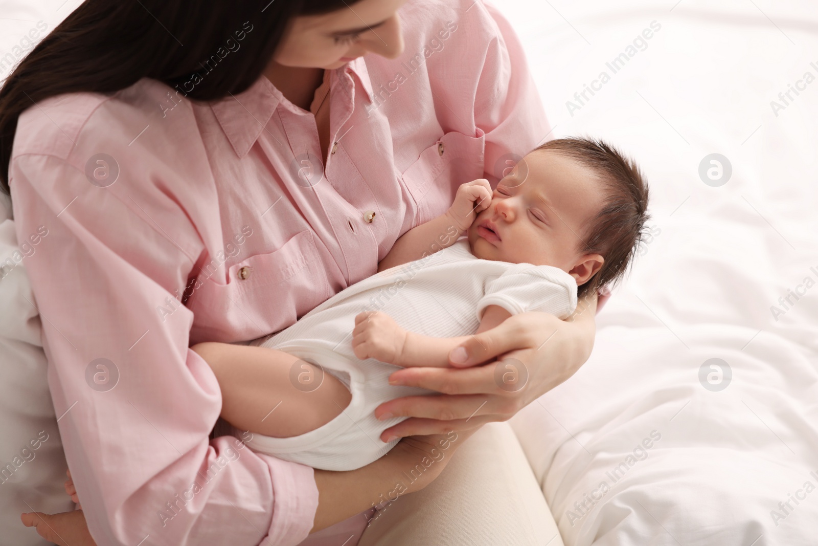 Photo of Mother with her sleeping newborn baby on bed