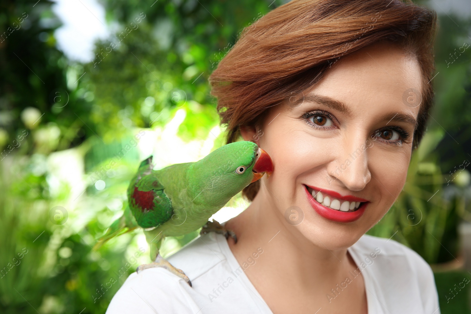 Photo of Happy woman with Alexandrine parakeet on blurred background