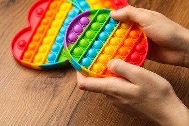 Woman using pop it fidget toy at wooden table, closeup