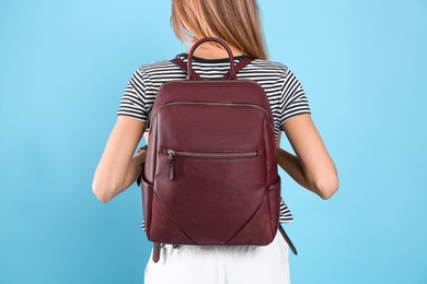 Photo of Woman with backpack on light blue background, closeup. Back view