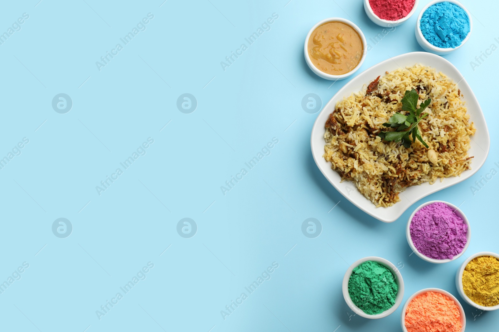 Photo of Flat lay of traditional Indian food and color powder dyes on turquoise background, space for text. Holi festival
