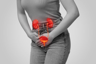 Woman suffering from cystitis on light background, closeup. Illustration of urinary system