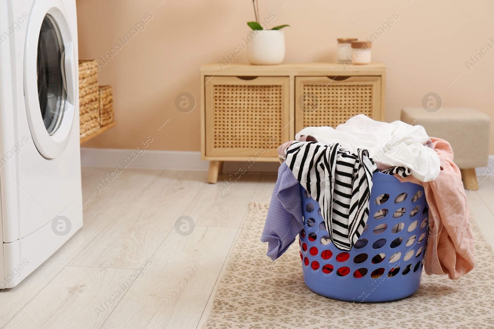 Photo of Plastic laundry basket overfilled with clothes in bathroom