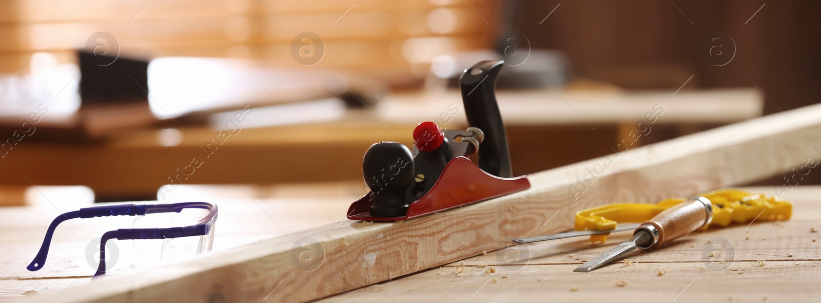 Image of Different carpenter's tools and wooden bar on table in workshop. Banner design