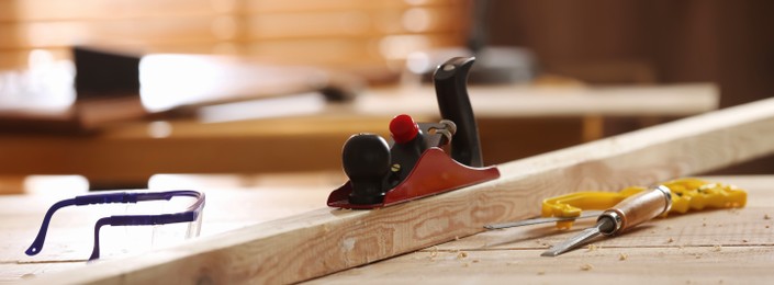 Image of Different carpenter's tools and wooden bar on table in workshop. Banner design