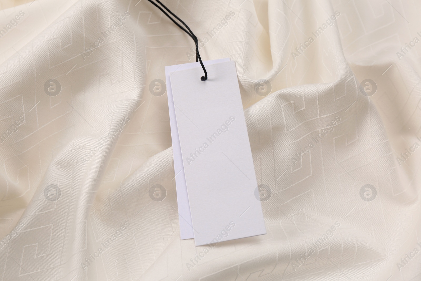 Photo of Blank tags on white fabric, top view. Space for text