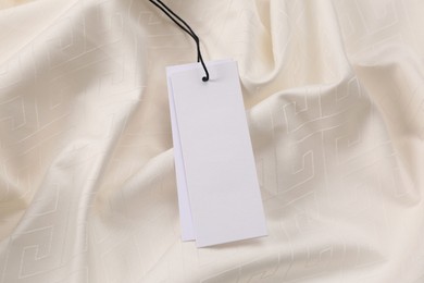 Blank tags on white fabric, top view. Space for text