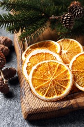 Photo of Dry orange slices, cones and fir tree branches on grey table, closeup