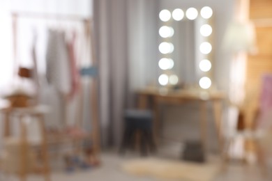 Photo of Blurred view of makeup room with stylish mirror, dressing table and chair