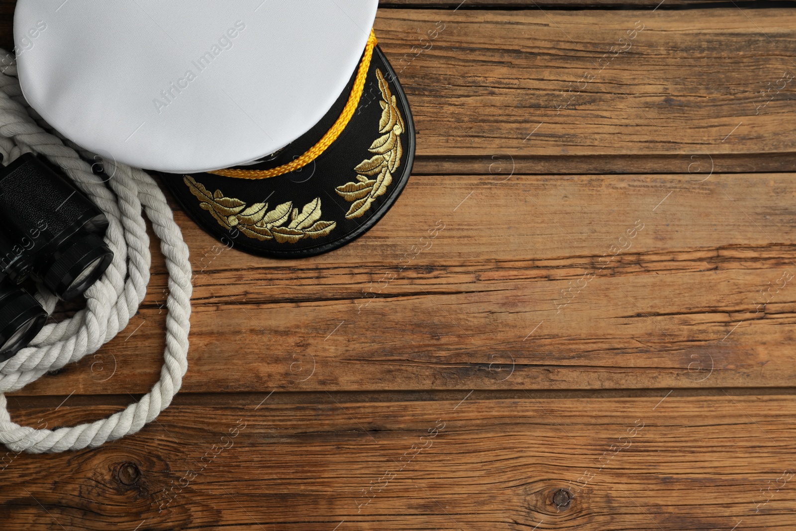 Photo of Peaked cap, rope and binoculars on wooden background, flat lay. Space for text