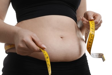 Photo of Woman measuring belly with tape on white background, closeup. Overweight problem