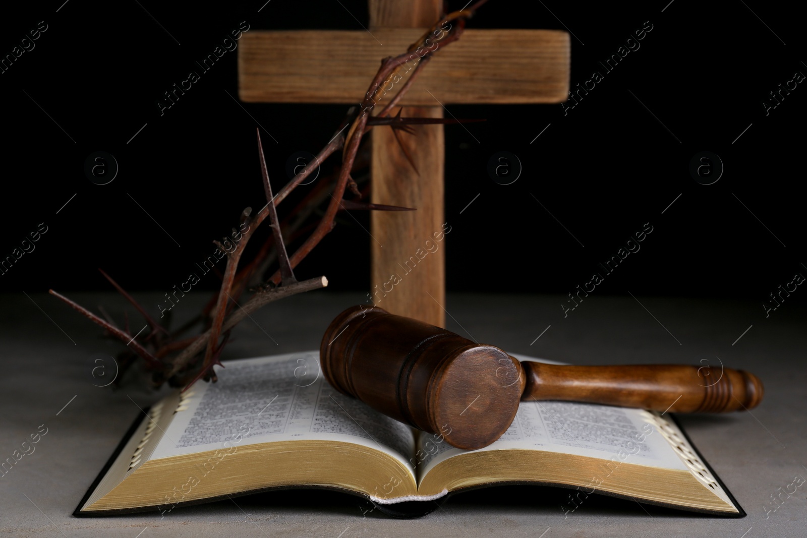 Photo of Judge gavel, bible, wooden cross and crown of thorns on grey table