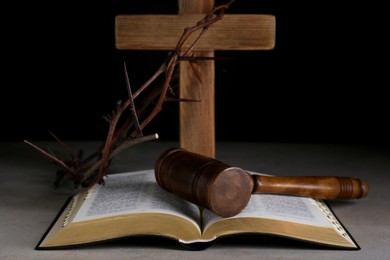 Judge gavel, bible, wooden cross and crown of thorns on grey table