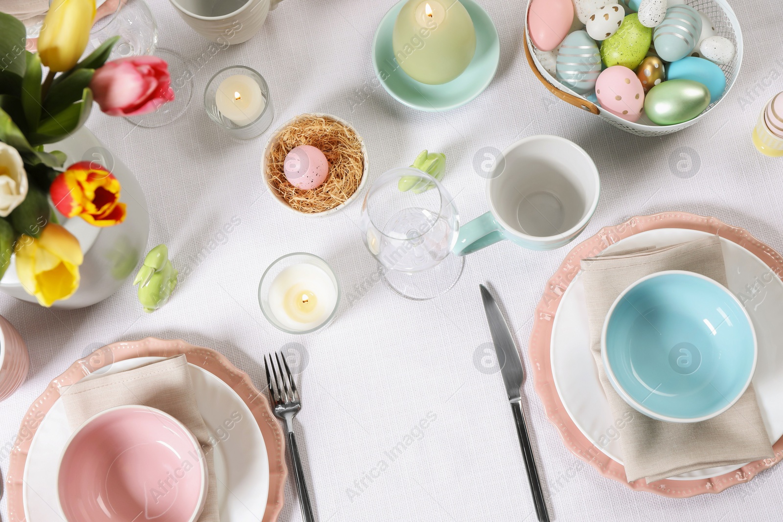 Photo of Festive table setting with painted eggs, flat lay. Easter celebration