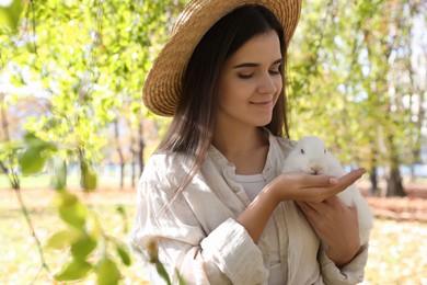 Woman holding cute white rabbit in park