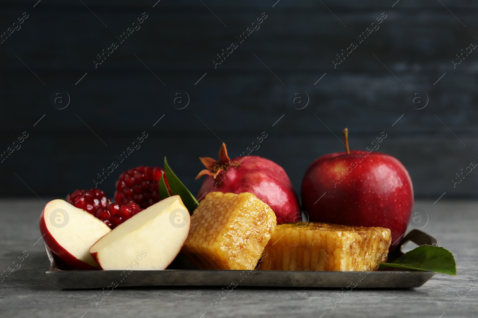 Photo of Honeycombs, apples and pomegranate on grey table. Rosh Hashanah holiday