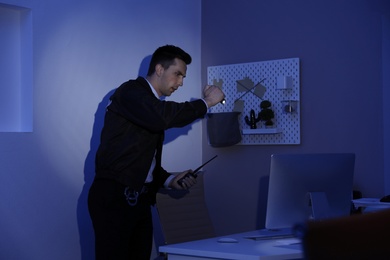 Male security guard with flashlight and portable radio transmitter in dark room