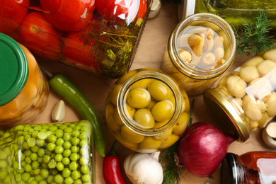 Photo of Glass jars with tasty pickled food on wooden background, flat lay