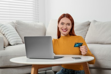 Photo of Happy woman with credit card using laptop for online shopping at home