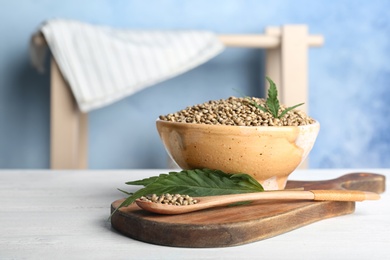 Photo of Bowl of hemp seeds on table against color background