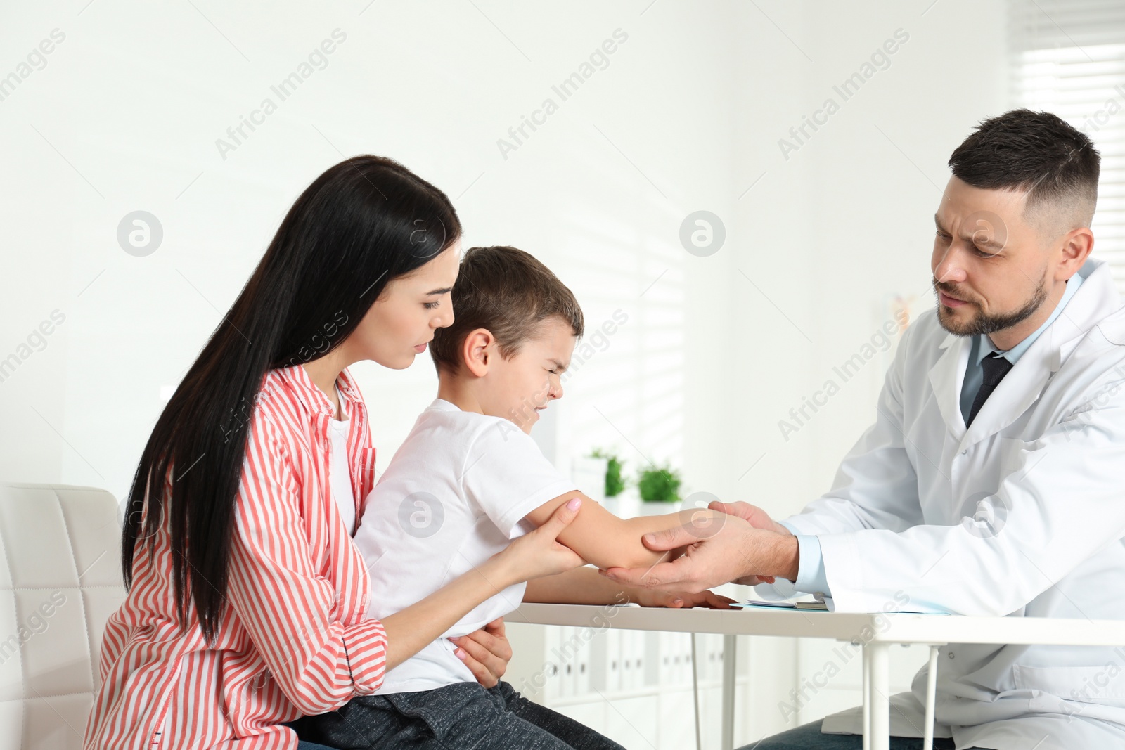 Photo of Little boy with mother visiting orthopedist at clinic