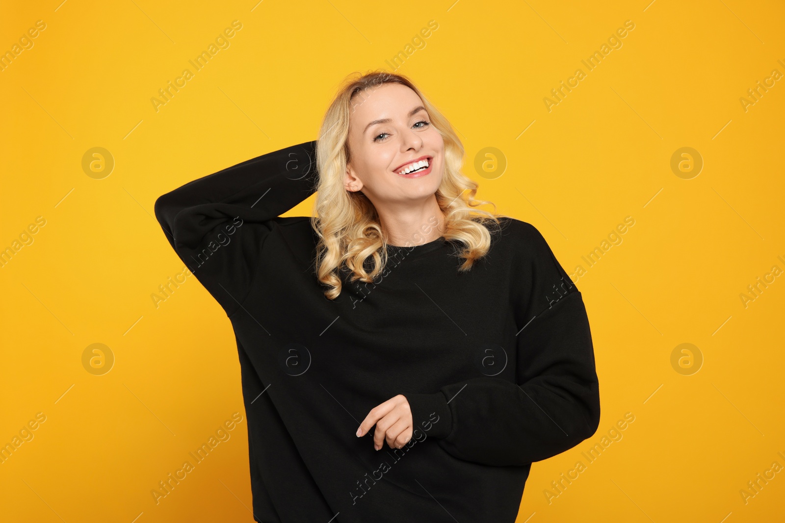 Photo of Happy woman in stylish warm sweater on orange background