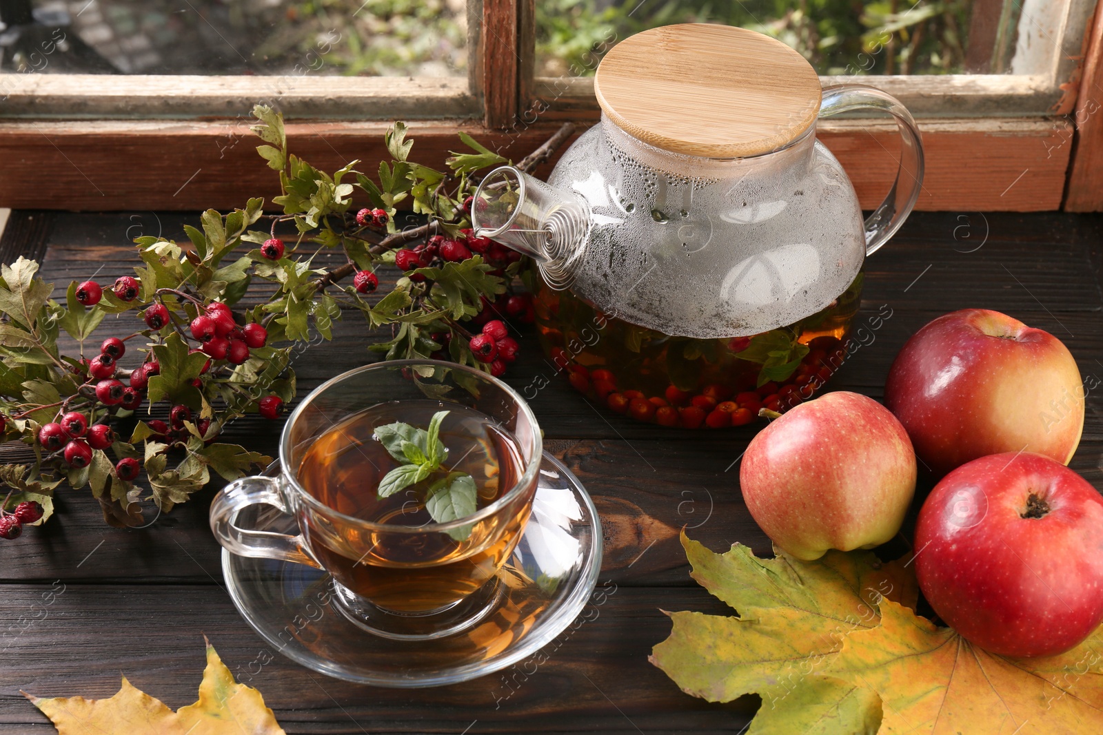 Photo of Hot tea, apples and dry leaves on wooden windowsill, above view. Autumn atmosphere