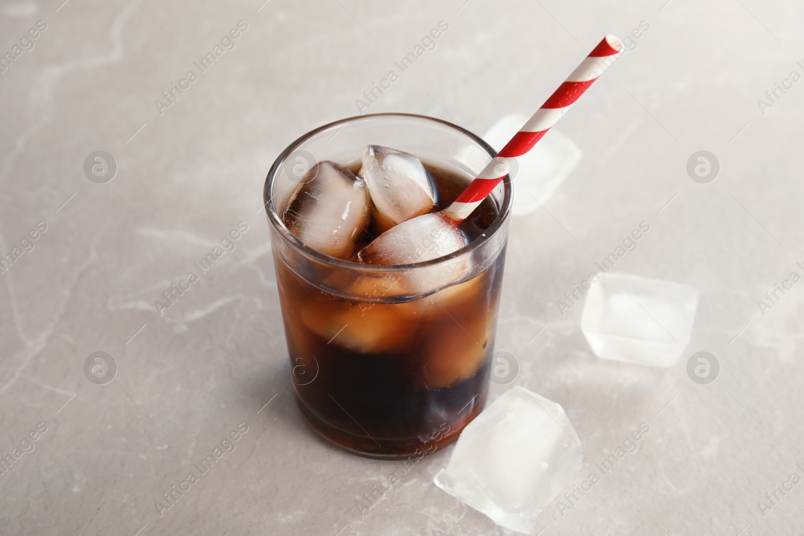 Photo of Glass of refreshing cola with ice on grey background