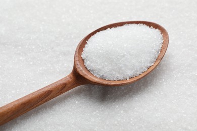 Wooden spoon on granulated sugar, closeup view