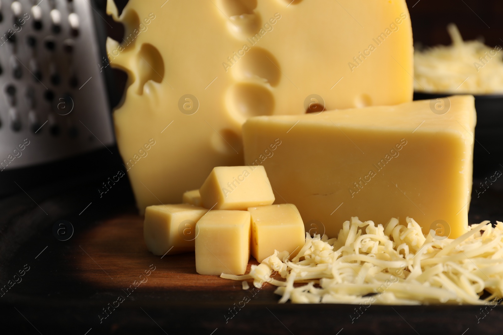 Photo of Grated, cut cheese and grater on table, closeup