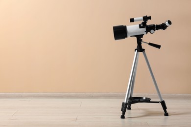 Photo of Tripod with modern telescope near beige wall. Space for text
