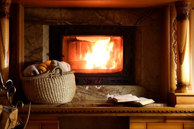 Sweaters, books and firewood near fireplace at home
