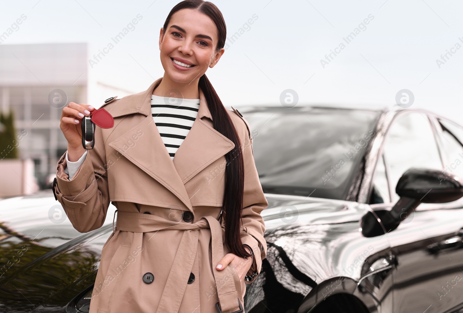 Photo of Woman holding car flip key near her vehicle outdoors