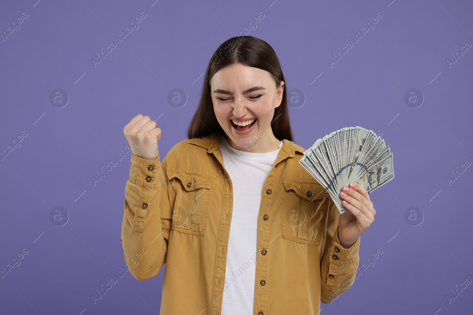 Photo of Excited woman with dollar banknotes on purple background