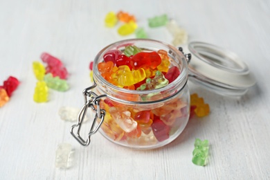 Glass jar with delicious jelly bears on wooden table