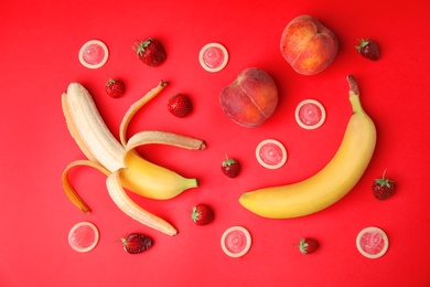 Photo of Flat lay composition with condoms and exotic fruits on red background. Erotic concept