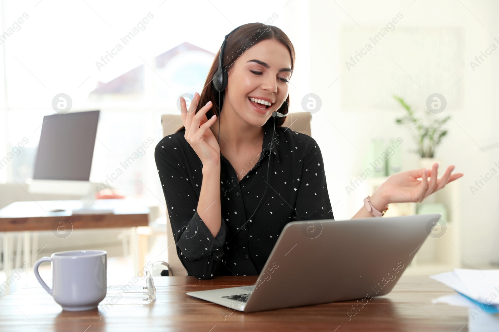 Photo of Young woman using video chat on laptop in home office